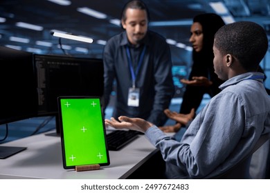 Focus on green screen tablet used by team in blurry background reconfiguring server farm to optimize it for data processing. Close up of mockup device used by workers overseeing data center equipment - Powered by Shutterstock