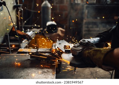 Focus on a grinding machine grinding the metal plate while the golden sparks flying in all directions. Working with the electric tools in the industrial facility. Metal processing with angle grinder. - Powered by Shutterstock