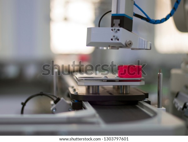Focus on a gripper. Industry 4.0 concept;\
artificial intelligence in manufacturing. Gripper picks up the\
product from automated car on the manufacturing line in a smart\
factory. Selective focus.