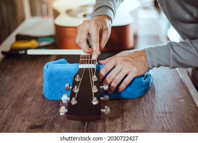 Focus on the guitar repairman's hand, Technician adjusting acoustic guitar neck, Close-up.