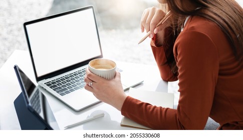 focus on hand young asian businesswoman holding pen and thinking her plan while she working or meeting online with laptop and other hand holding coffee cup