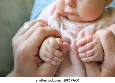 Focus On The Hands Of A 3 Month Old Baby Girl Holding The Fingers Of Her Father.