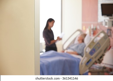 Focus On Hospital Room Sign With Doctor Talking To Patient