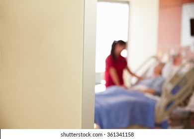Focus On Hospital Room Sign With Nurse Talking To Patient
