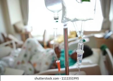 Focus On Iv Drip Chamber And Iv Bag Of Solution With Patient On Bed Blurd Background In Patient Room Hospital