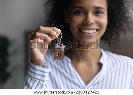 Focus on keys in female hands, smiling young african american mixed race woman feeling excited of buying own dwelling, purchasing or selling apartments, satisfied with professional real estate service