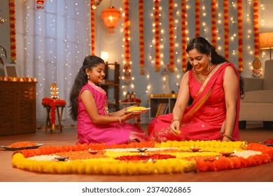 focus on kid,Happy Indian young Mother with daughter preparing Diwali rangoli for celebration - concept of home decoration, family bonding and religious custom. - Powered by Shutterstock