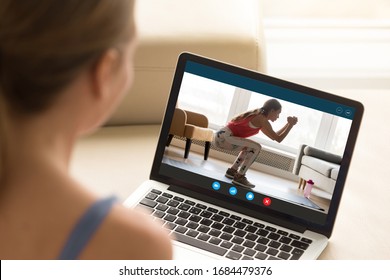 Focus on laptop screen with young woman in sportswear doing morning exercises, deep squats on yoga mat, staying fit at home. Interested girl watching online educational fitness workshop training. - Shutterstock ID 1684479376