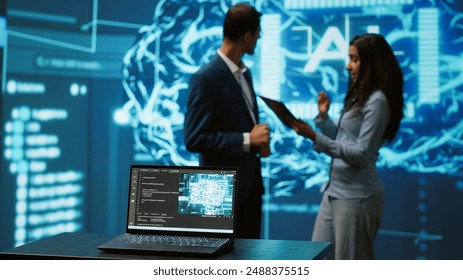Focus on laptop in workspace used by AI researchers working with artificial intelligence in blurry background. Close up of notebook used by employees developing AI systems in tech startup, camera A