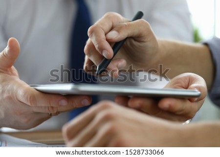Focus on male hand pointing at screen of modern tablet with stylos. Biz colleagues discussing signing future bargain. Business negotiations concept. Blurred background