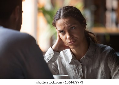 Focus on mixed race irritated young female sitting in cafeteria on speed dating with boring male rear view. Unsuccessful unlucky romantic date failure, bad first impression and poor companion concept