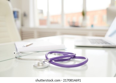 Focus On Modern Stethoscope With Purple Rubber Tube Placed On Doctors Table In Office Full Of Light