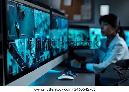 Focus on one of several computer screens with cctv video on workplace of modern security guard with female officer on background