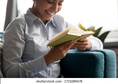 Focus on paper book in hands of happy millennial indian woman. Smiling young hindu ethnic girl reading favorite novel story, resting alone on comfortable couch in living room, hobby pastime concept. - Shutterstock ID 1721089678