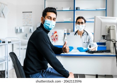 The Focus Is On The Patient In A Protective Mask At The Doctor's Appointment, A Satisfied Patient, A Professional Doctor, A Modern Hospital.