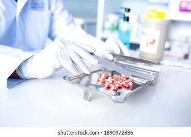 Focus on the picture of the doctor's hand, the colored pill on the dispensing tray by an antiviral drug pharmacist.
 - Powered by Shutterstock