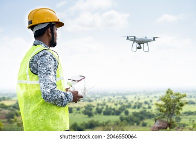 Focus On Pilot, Pilot With Safety Hardhat Flying Drone Using Remote Controller - Concept Of Engineer Doing Aerial Survey Or Inspection Using UAV