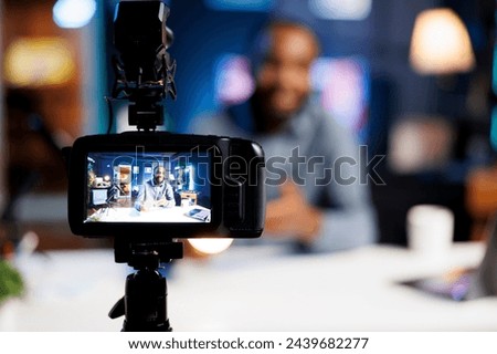 Focus on professional camera capturing footage of content creator in blurry background filming tech tutorial on how to do smart light bulb maintenance, teaching viewers about IoT home automation