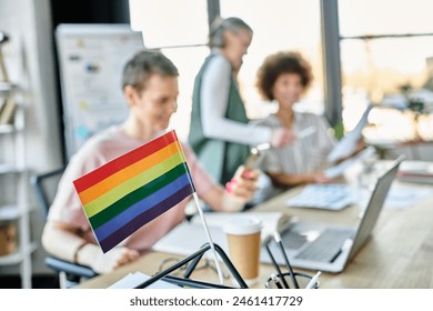 Focus on rainbow flag displayed on office table in front of blurred dverse businesswomen. - Powered by Shutterstock