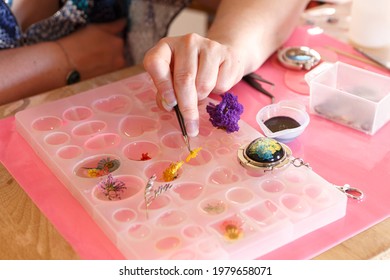 Focus on a resin jewelry creation process, Close-up photo of the hands pouring transparent resin into a cell to design a piece of jewelry.