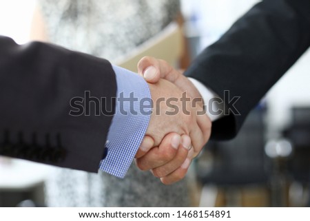 Focus on shake hands of two businessmen performing gesture of mutual agreement in complicated and important business meeting. Biz concept. Blurred background