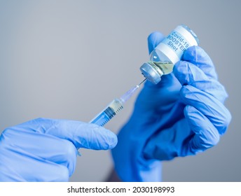 Focus on syringe, close up of doctor or nurse hands taking covid vaccination booster shot or 3rd dose from syringe. - Shutterstock ID 2030198993