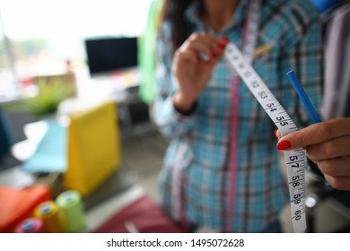 Focus On Tender Female Hands Holding Important Measuring Utility And Wearing Fashionable Clothes. Witty Girl Working On Significant Project. Fashioner Workshop Concept . Blurred Background