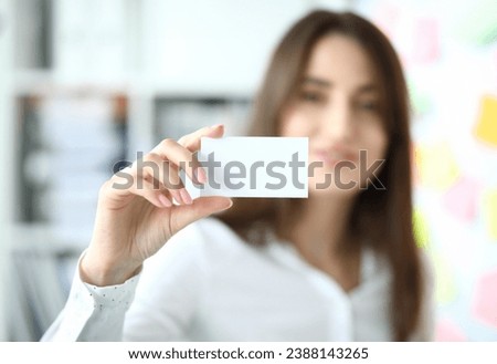 Focus on tender hand of smiling businesswoman showing special blank business card to friendly colleague or partner. Copy space on biz pasteboard. Blurred background
