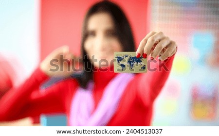 Focus on tender lady hand with red manicure of smart young woman showing golden bank master-card. Happy girl wearing fashionable outfit. Shopping concept. Blurred background