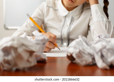 Focus on the top of the pencil. Little girl thinking hard, failed many times while writing composition on the difficult subject, can't take herself in hand and do the task - Powered by Shutterstock