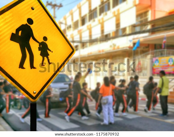 Focus on traffic security\
school sign with blurred background of many students are crossing\
the crosswalk to our school, close up shot with signs and symbols\
concept 