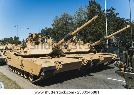Focus on two M1 Abrams main battle tanks driving in a column during an open-air military parade in Poland. High quality photo