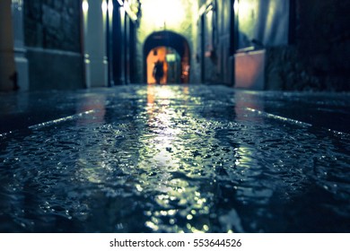 Focus on wet ground along dark medieval alley on a rainy night, Butter Slip, Kilkenny Ireland. 