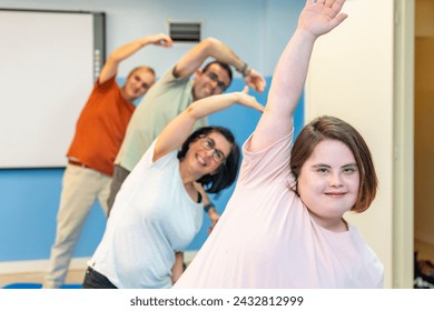 Focus on a woman with down syndrome and a group of people with special needs stretching in the gym - Powered by Shutterstock