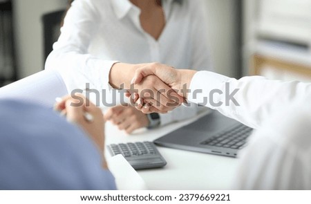 Focus on women shaking hands after signing profitable bargain. Business negotiations concept. Biz making good contract between partners. Blurred background