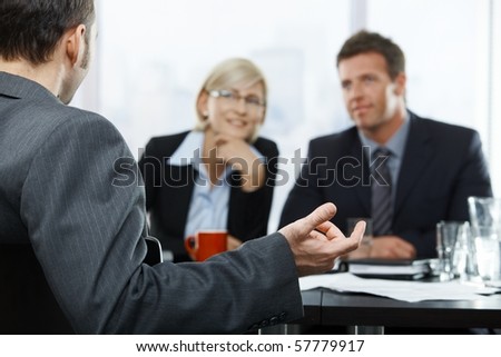Focus placed on hand gesturing to colleagues in the background at businessmeeting.?
