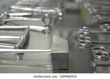 Focus selective on a stainless steel table, the forensic tools are exposed, scissors, scalpels, hammer, etc - Shutterstock ID 2209483555
