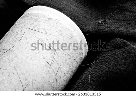 Focus stack of a lint roller resting on a dark suit jacket to remove pet animal hair. 