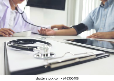 Focus of stethoscope, Competent attentive doctor being measuring blood pressure to patient, hospital and medicine concept.