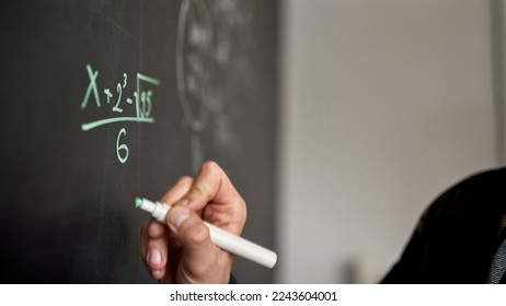 Focus of technical or math formula writing blurred cropped man with marker on blackboard in audience or classroom. IT, technical and engineering education. School, college, institute, univercity