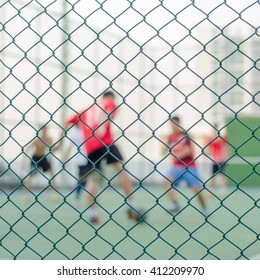 Focus of wired fence and blur image of People are playing futsal. Exercise after work
