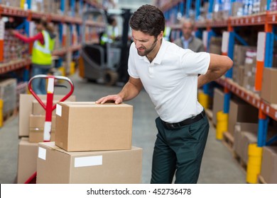 Focus of worker having a backache in a warehouse