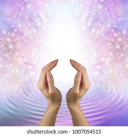 Focus your mind on sending pure healing love - female hands in cupped position against a beautiful feminine shimmering sparkle and water ripple background depicting unconditional love

