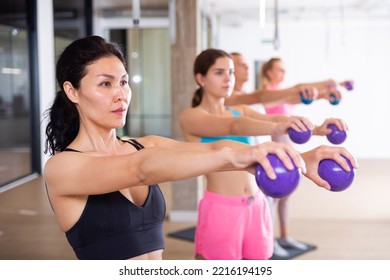 Focused Active Young Adult Woman Doing Workout With Toning Weight Balls At Group Pilates Class