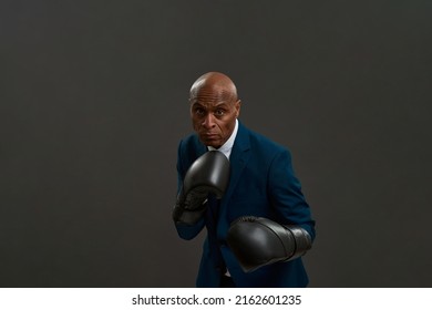 Focused african american businessman boxing. Adult man wearing suit and boxing gloves. Modern successful male lifestyle. Concept of business goal. Leadership. Grey background. Studio shoot. Copy space - Powered by Shutterstock