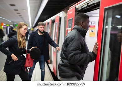 Focused African American Man In Warm Jacket Getting On Modern Subway Car With Other Passengers. Concept Of Daily City Trips