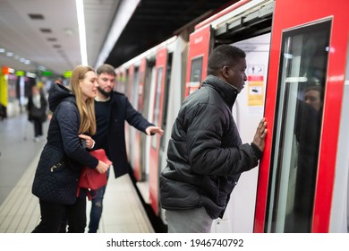 Focused African American Man In Warm Jacket Getting On Modern Subway Car With Other Passengers. Concept Of Daily City Trips