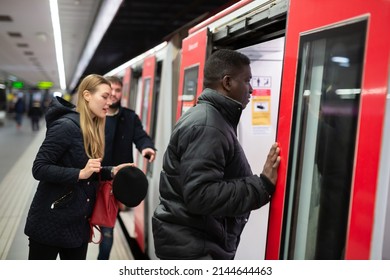 Focused African American Man In Warm Jacket Getting On Modern Subway Car With Other Passengers. Concept Of Daily City Trips