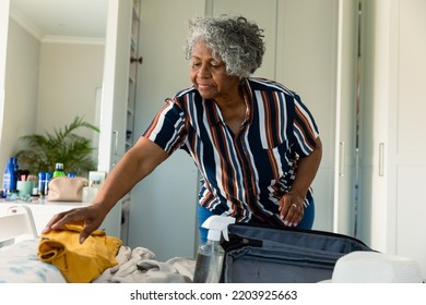 Focused african american senior woman packing suitcase in bedroom. travel preparation during covid 19 pandemic. - Powered by Shutterstock
