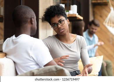 Focused African American woman talking with man in cafe, girlfriend discussing relationships with boyfriend, explaining, gesticulating, friends having serious conversation, sitting together on couch